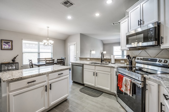 kitchen with white cabinets, stainless steel appliances, a notable chandelier, sink, and lofted ceiling