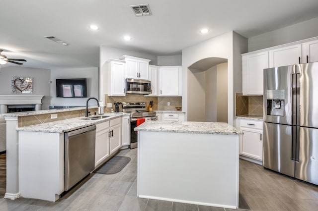 kitchen with stainless steel appliances, white cabinetry, sink, kitchen peninsula, and ceiling fan