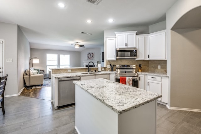 kitchen featuring stainless steel appliances, light hardwood / wood-style floors, sink, kitchen peninsula, and ceiling fan