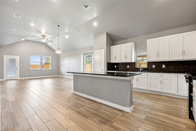 kitchen with white cabinets, ceiling fan, light hardwood / wood-style floors, and vaulted ceiling