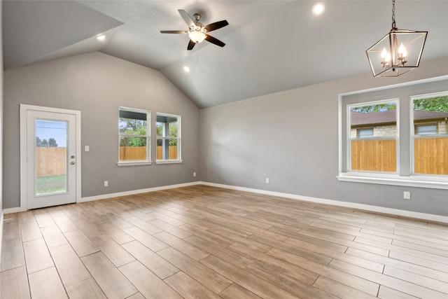 unfurnished room with ceiling fan with notable chandelier, light wood-type flooring, lofted ceiling, and plenty of natural light