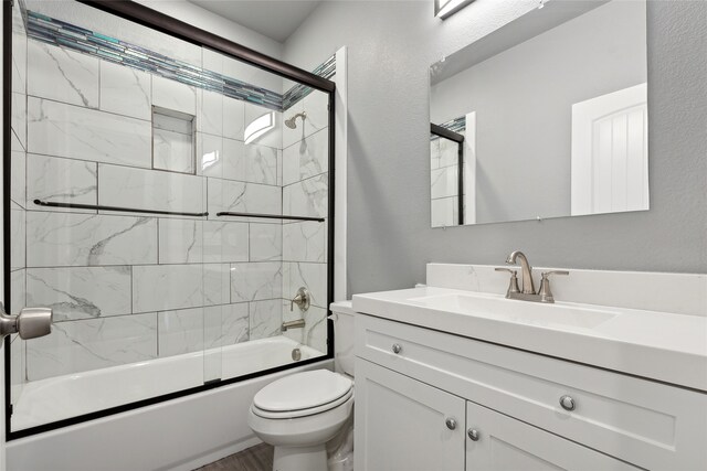 full bathroom with enclosed tub / shower combo, toilet, and vanity