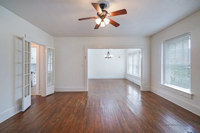 empty room featuring ceiling fan with notable chandelier, dark hardwood / wood-style floors, and french doors