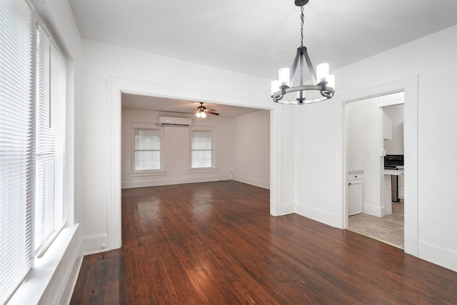 unfurnished living room with dark hardwood / wood-style floors, ceiling fan with notable chandelier, and a wall unit AC