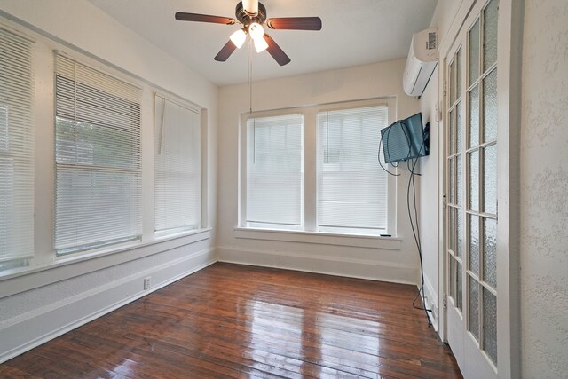 unfurnished sunroom with ceiling fan and a wall unit AC