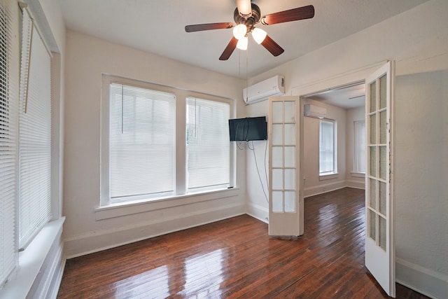 empty room with dark wood-type flooring, a wall unit AC, and ceiling fan