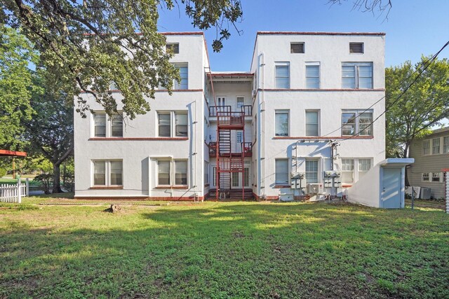 rear view of property featuring a balcony, central AC unit, and a lawn