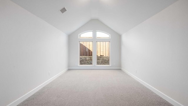 empty room with light colored carpet and lofted ceiling