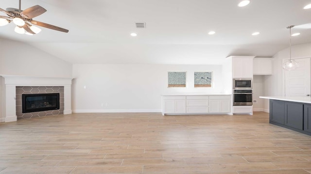 unfurnished living room with a fireplace, ceiling fan, and vaulted ceiling