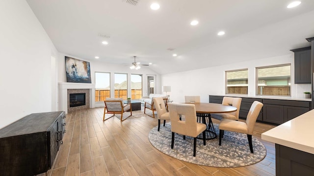 dining room with ceiling fan, lofted ceiling, and light wood-type flooring