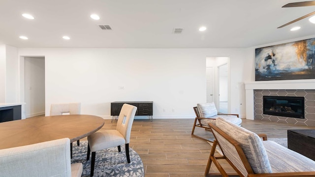 dining space featuring ceiling fan and a tiled fireplace