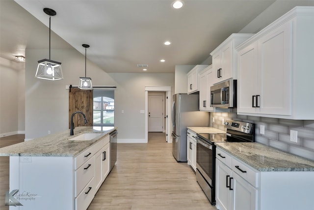 kitchen featuring white cabinets, light wood-type flooring, stainless steel appliances, sink, and pendant lighting