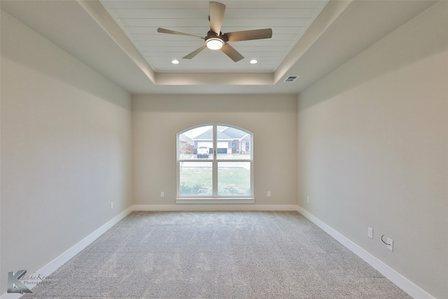 carpeted empty room featuring a raised ceiling, ceiling fan, and wooden ceiling