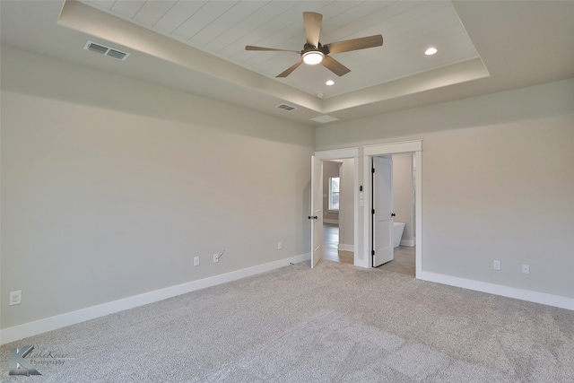 interior space featuring a tray ceiling, ceiling fan, wood ceiling, and light carpet