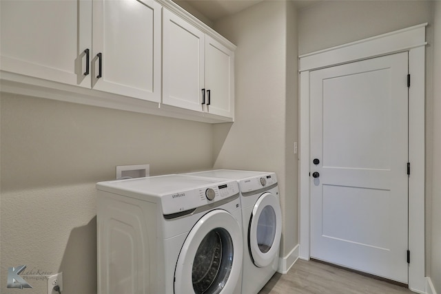 laundry room with washer and dryer, cabinets, and light hardwood / wood-style flooring