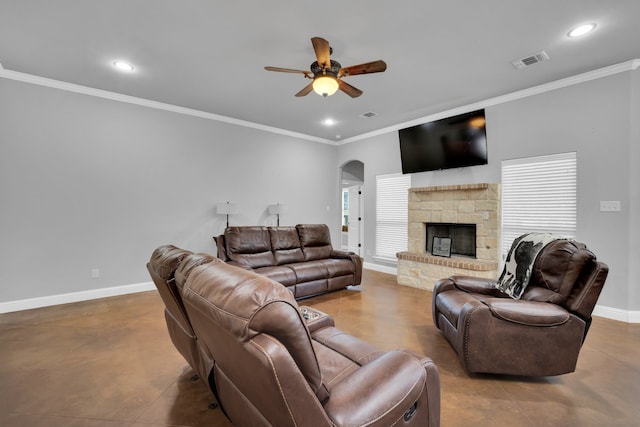 living room with ceiling fan, ornamental molding, a stone fireplace, and concrete flooring