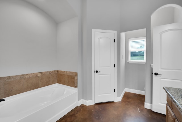 bathroom featuring vanity, a tub, and concrete flooring