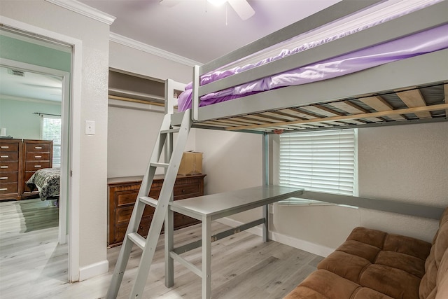 bedroom featuring crown molding, light hardwood / wood-style flooring, a closet, and ceiling fan