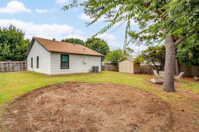 rear view of house featuring a lawn, a storage unit, and central AC unit