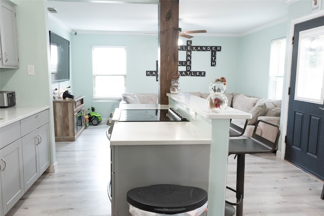 kitchen with breakfast area, ornamental molding, gray cabinets, and a breakfast bar area