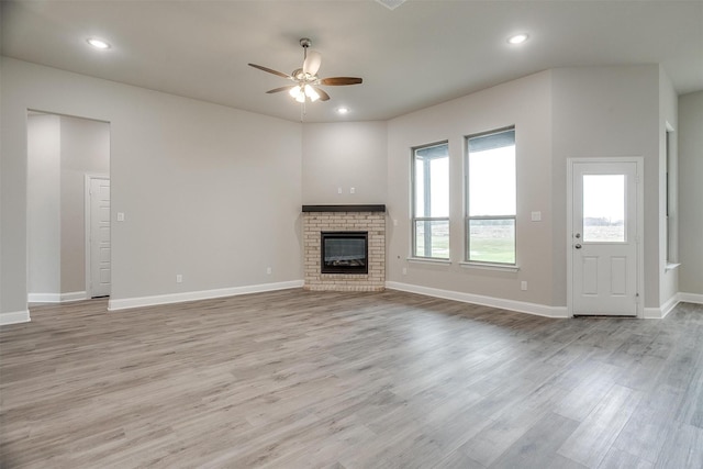 unfurnished living room featuring a fireplace, light wood-type flooring, and ceiling fan