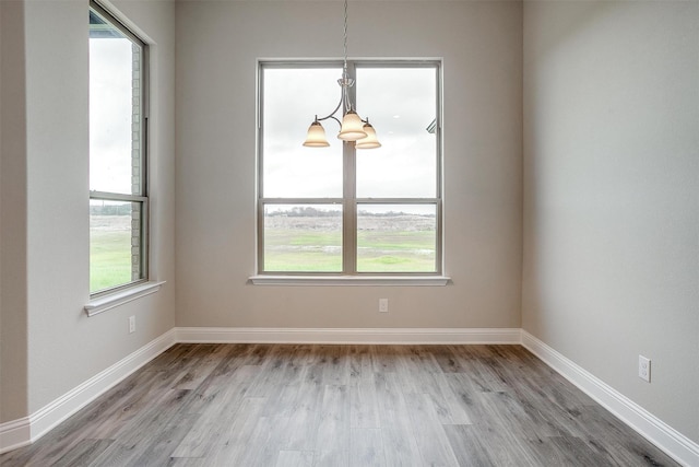 unfurnished dining area featuring a chandelier and light hardwood / wood-style flooring