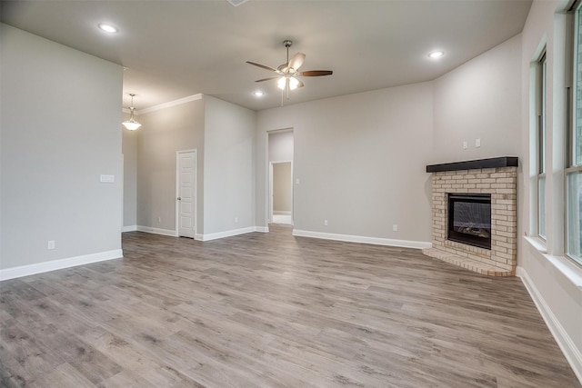 unfurnished living room with hardwood / wood-style floors, ceiling fan, a brick fireplace, and ornamental molding