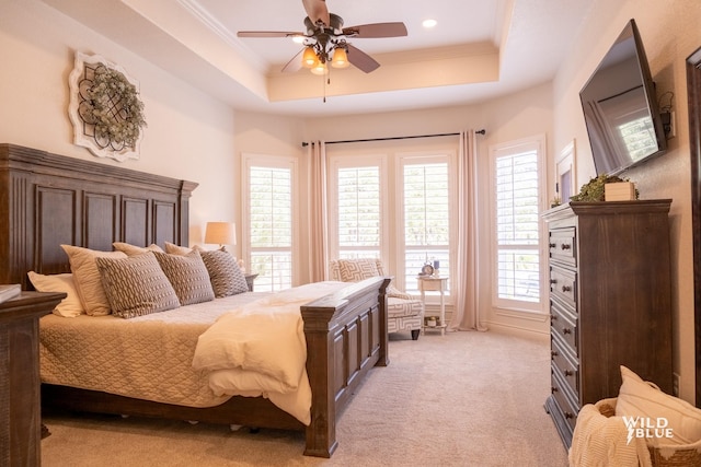 bedroom featuring crown molding, a tray ceiling, light carpet, and ceiling fan