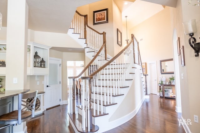 stairs featuring hardwood / wood-style flooring and a high ceiling