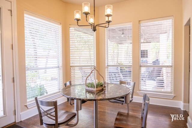 dining area featuring dark wood-type flooring, a wealth of natural light, and an inviting chandelier