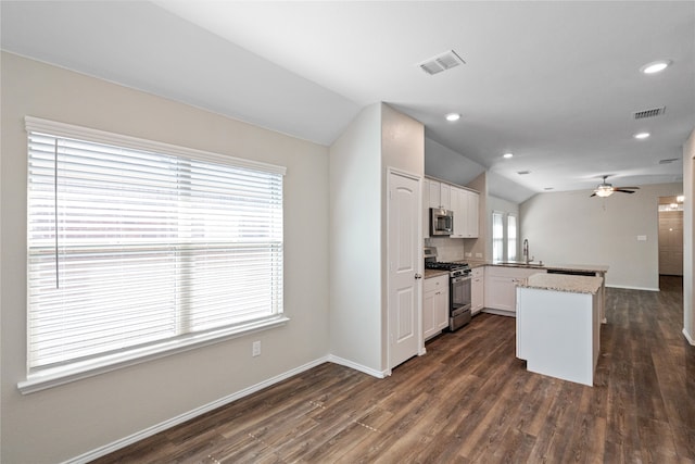 kitchen with white cabinets, appliances with stainless steel finishes, vaulted ceiling, dark wood-type flooring, and sink