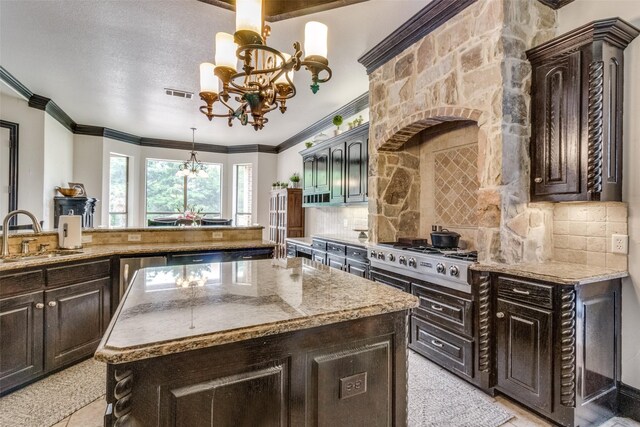 kitchen featuring a notable chandelier, tasteful backsplash, stainless steel appliances, a kitchen island, and sink