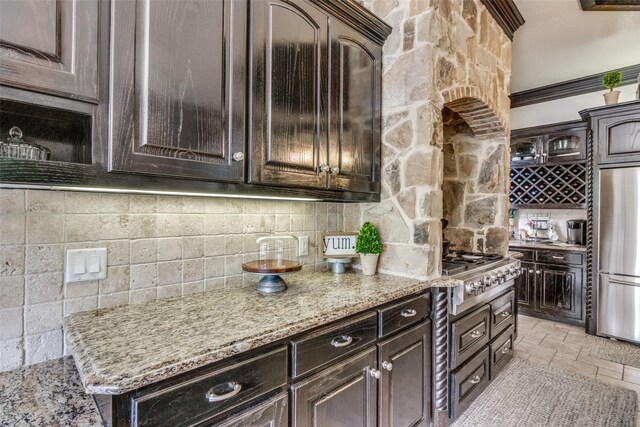 kitchen with crown molding, dark brown cabinets, light stone counters, and stainless steel appliances