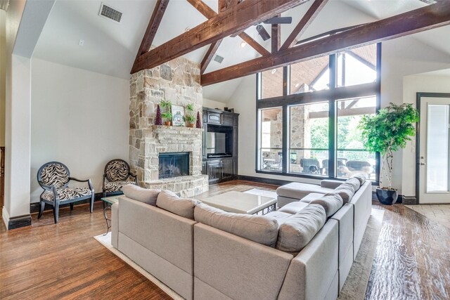 living room featuring wood-type flooring, high vaulted ceiling, beam ceiling, and a fireplace