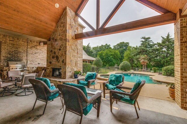 view of patio / terrace featuring a fenced in pool, an outdoor living space with a fireplace, and an outdoor kitchen