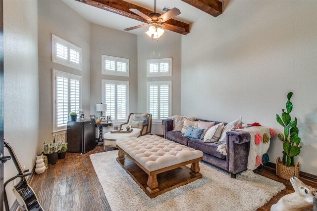 living room with ceiling fan, a towering ceiling, beamed ceiling, and wood-type flooring