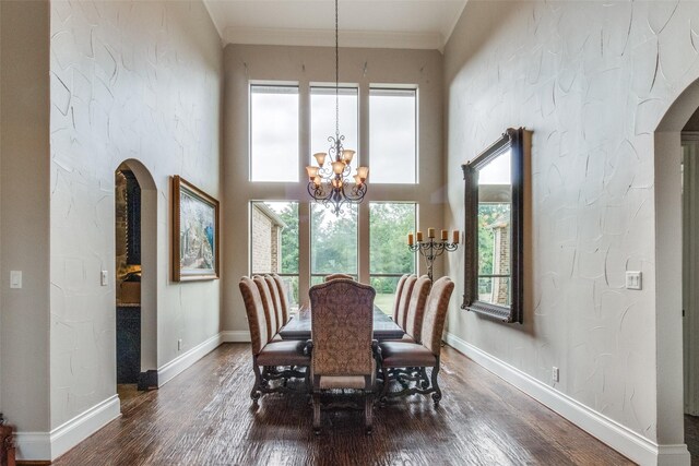 dining space featuring dark hardwood / wood-style floors, an inviting chandelier, and crown molding