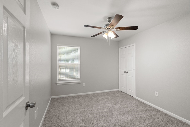 carpeted spare room with ceiling fan