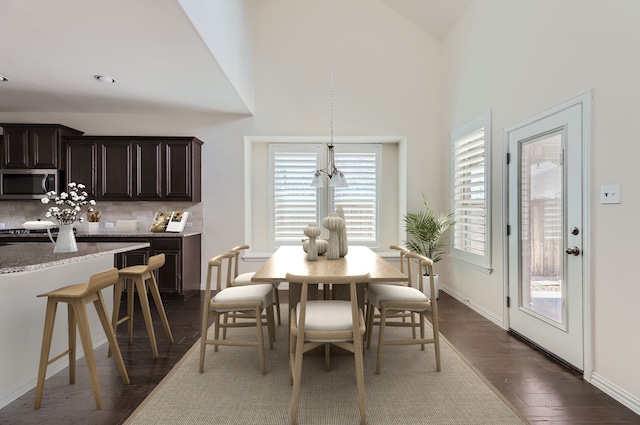 dining space with dark hardwood / wood-style flooring and high vaulted ceiling