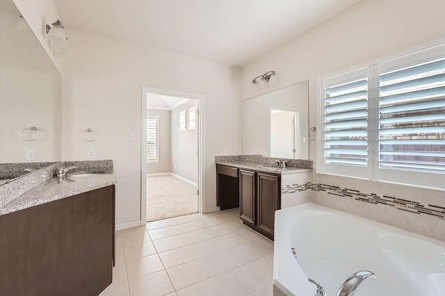 bathroom with tile patterned flooring, a bathing tub, and vanity