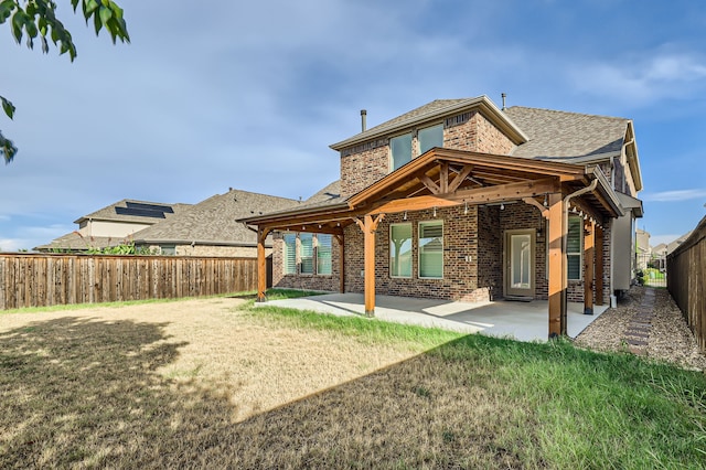 back of property with a yard and a patio