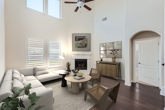 living room featuring ceiling fan, dark hardwood / wood-style floors, a high ceiling, and a wealth of natural light