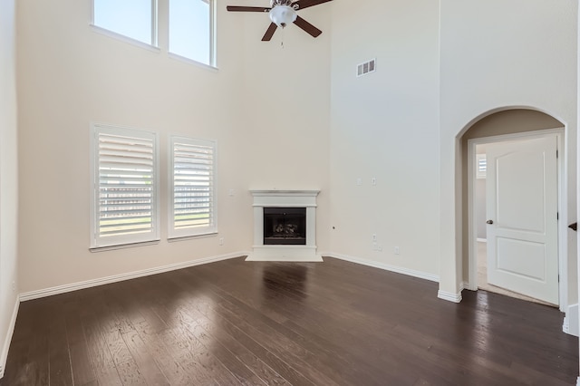 unfurnished living room with ceiling fan, dark hardwood / wood-style floors, and a towering ceiling