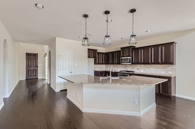 kitchen featuring pendant lighting, sink, stainless steel appliances, a center island with sink, and dark hardwood / wood-style flooring