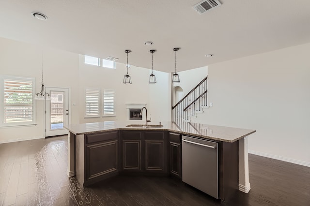 kitchen with a kitchen island with sink, sink, dark wood-type flooring, hanging light fixtures, and stainless steel dishwasher