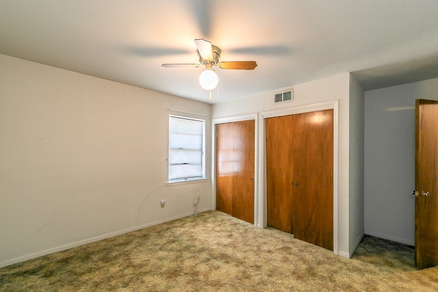 unfurnished bedroom with carpet flooring, ceiling fan, and multiple closets