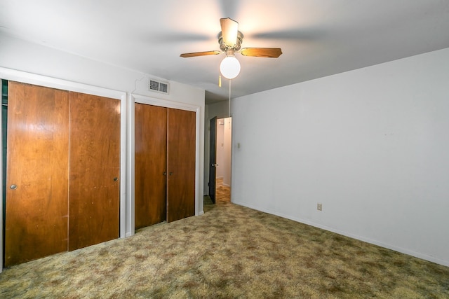 unfurnished bedroom with ceiling fan, carpet, and multiple closets