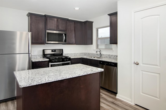 kitchen with light wood-type flooring, a center island, sink, appliances with stainless steel finishes, and dark brown cabinetry