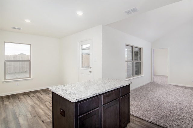 kitchen featuring lofted ceiling, a center island, hardwood / wood-style floors, and dark brown cabinetry