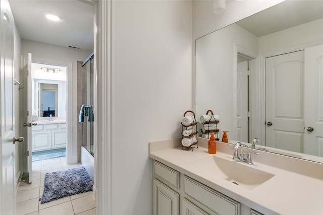 bathroom featuring tile patterned flooring, vanity, and bath / shower combo with glass door